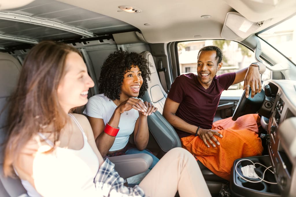 Amigos sorrindo dentro de uma van durante a viagem
