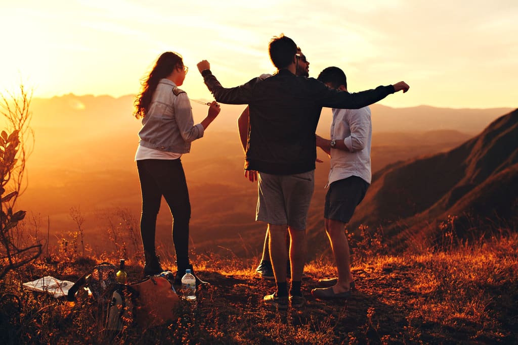 Amigos comemorando no alto de uma serra ao pôr do sol